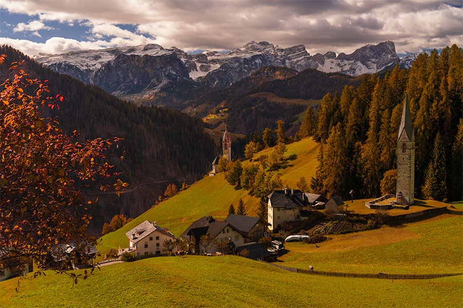 Fall light on Chiesa di Santa Barbara and surrounding alpine slopes in the Dolomites